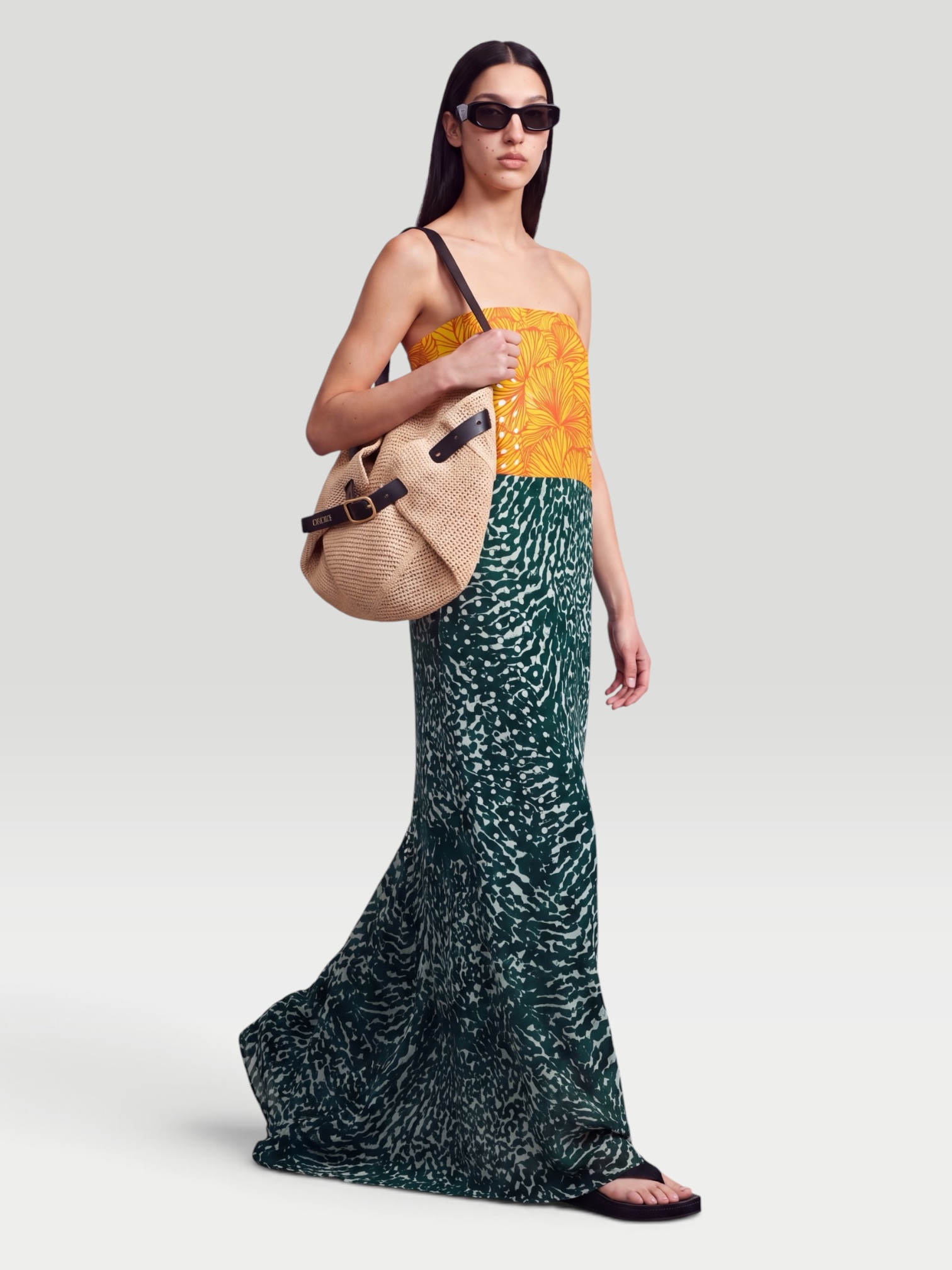 Dries Van Noten Printed Strapless Georgette Gown, worn with Phoebe Philo Frizz Flip Flop, Loewe Leather-Trimmed Raffia Tote, Phoebe Philo Peak Sunglasses, Sarah Creal Brilliant Repair Shield SPF 50 Illuminating Serum Broad Spectrum Sunscreen, on the water. Styled by Sharon Lombardo for FDV Concierge.