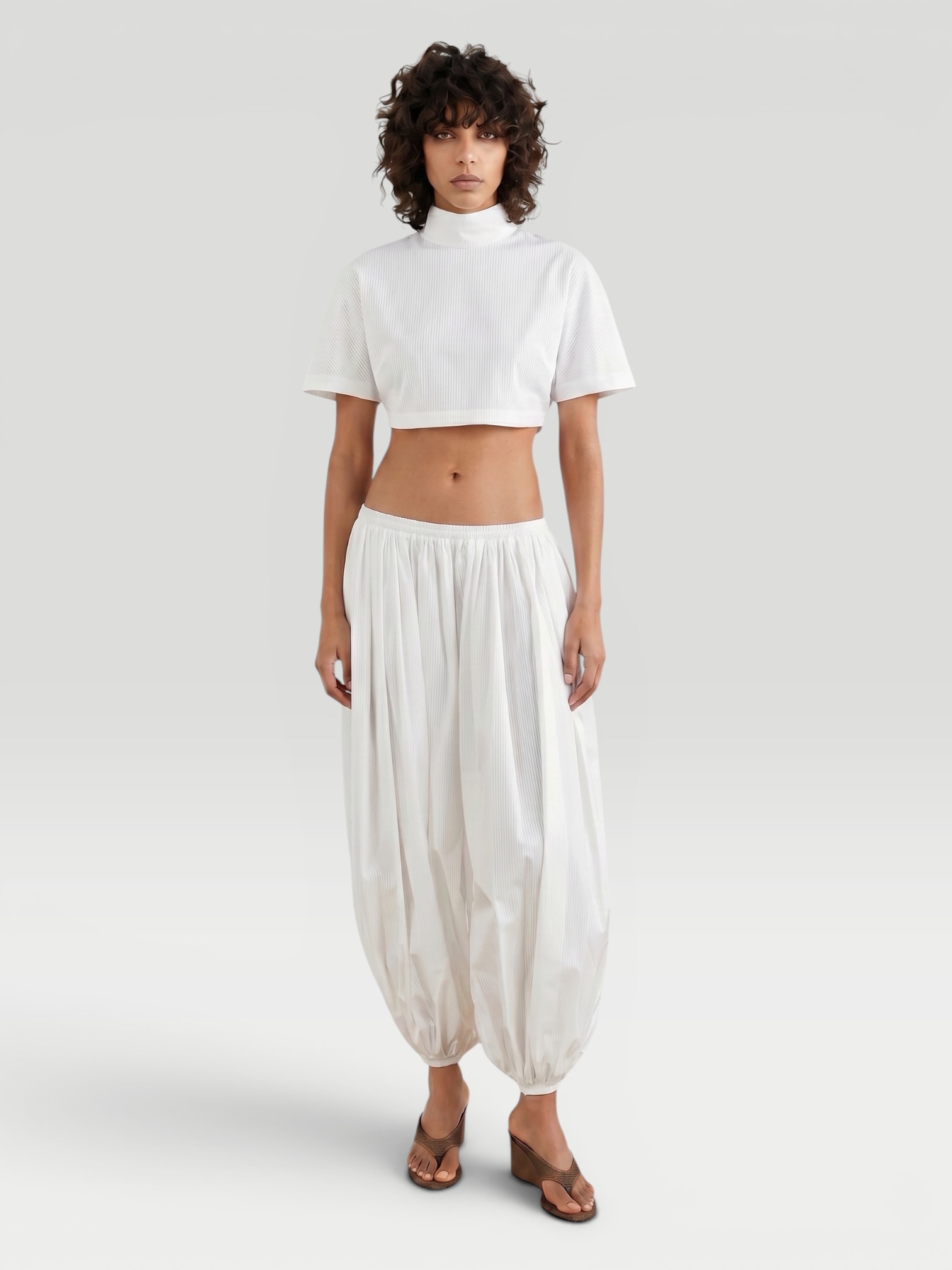 Alaïa Cropped Jersey Turtleneck Tee in white, worn with Alaïa Balloon Pants, Alaïa Wedge Thong Mule. Styled by Sharon Lombardo for FDV Concierge.