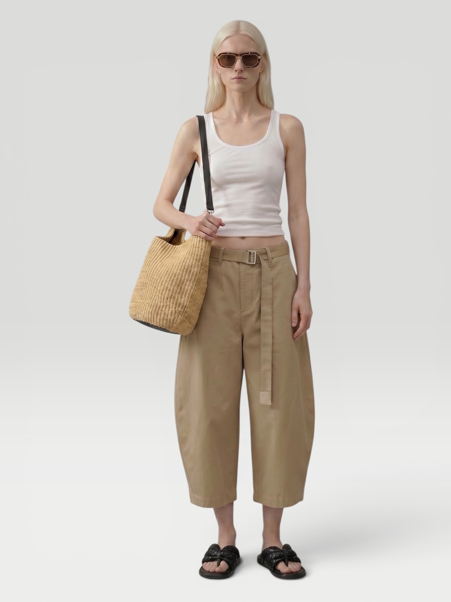 All Three Kristen Rib Tank in white, worn with Totême Wide Summer Trousers, St. Agni Fringed Leather Belt Skirt, Bottega Veneta Sampieri Flat Thong, Loewe Paula's Ibiza Punch Hole Small Leather-Trimmed Raffia Tote, on the water. Styled by Sharon Lombardo for FDV Concierge.