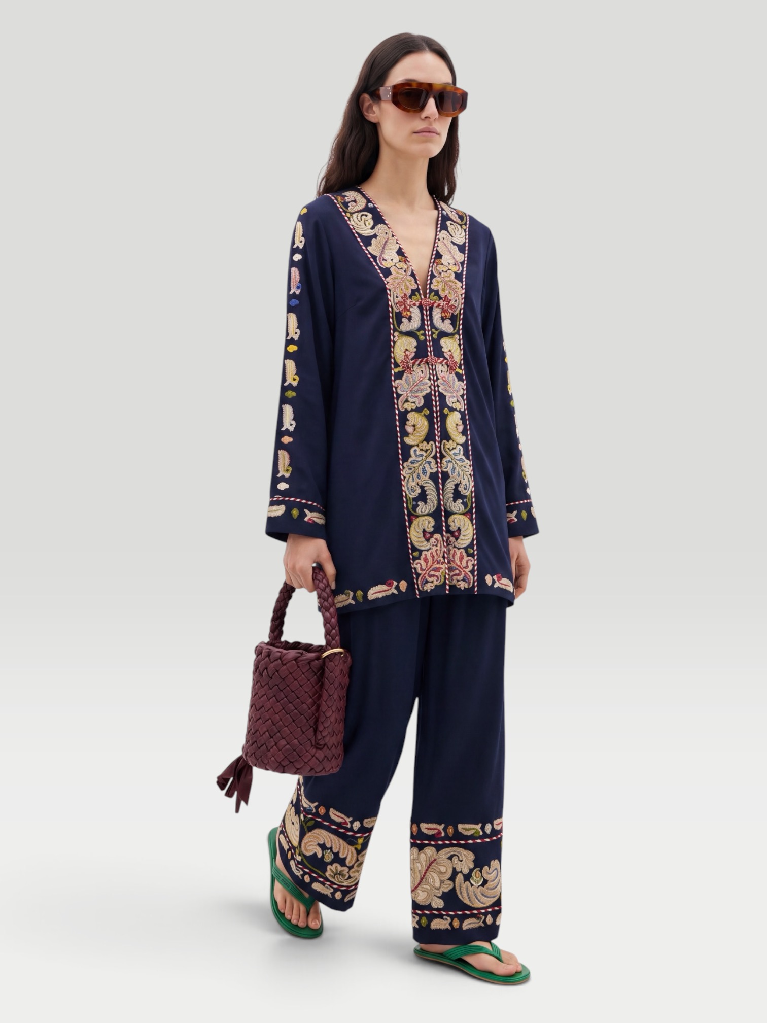 BODE Feather Runner Embroidered Cotton-Blend Twill Jacket in black, worn with BODE Feather Runner Embroidered Cotton-Blend Flared Pants, Dries Van Noten Oval Sunglasses, Bottega Veneta Kalimero Città Small Leather Shoulder Bag, Bottega Veneta Sampieri Flat Thong, on the water. Styled by Sharon Lombardo for FDV Concierge.