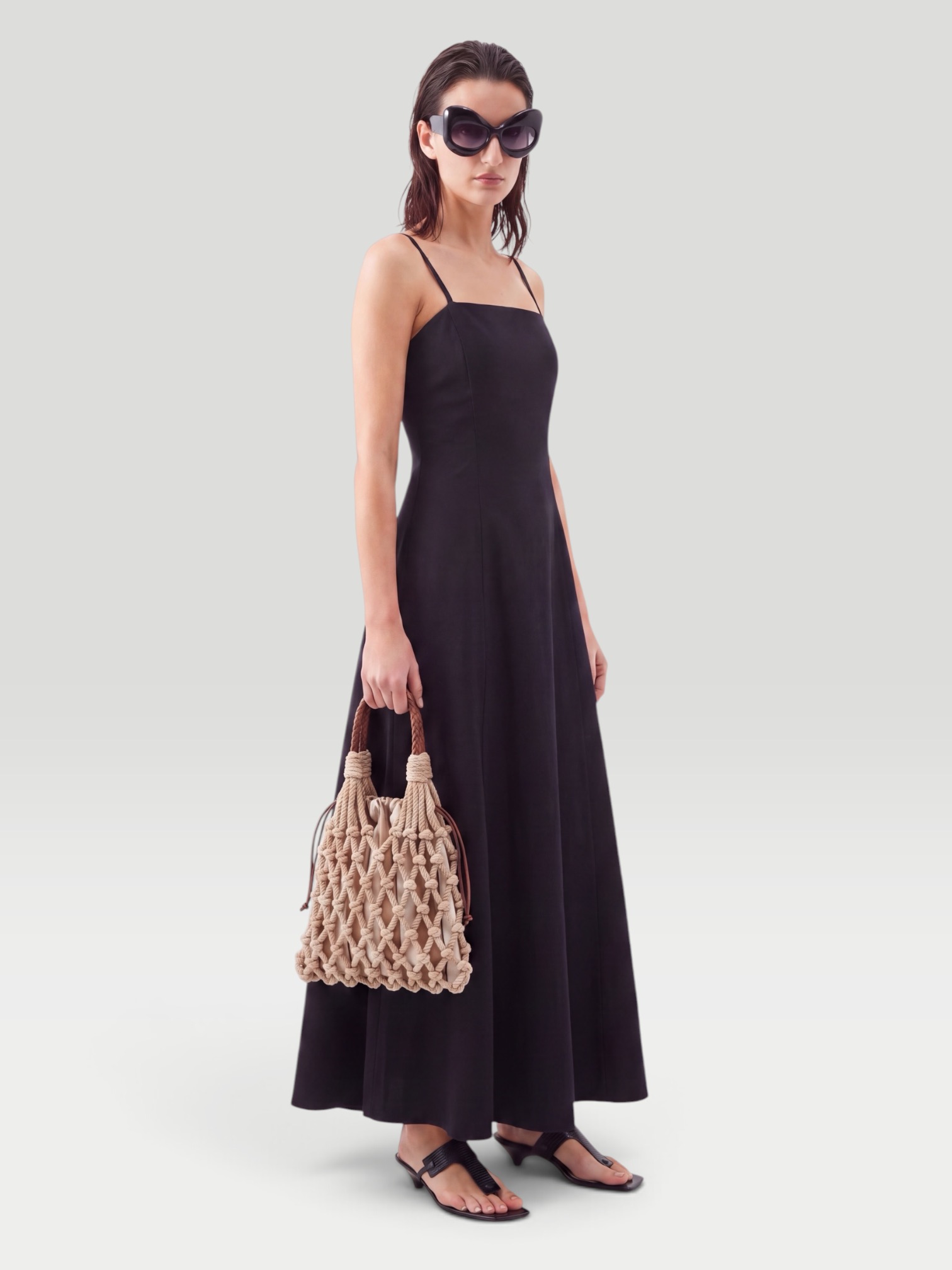 FFORME Neneh Cotton and Silk-Blend Maxi Dress in black, worn with CO Ankle Wrap Sandal, Jacques Marie Mage The Shining Round-Frame Acetate Sunglasses, Prada Noué Medium Cotton Macramé Bag, Love Adorned Vintage Mixed Cut Diamond Signet Ring, the evening. Styled by Sharon Lombardo for FDV Concierge.