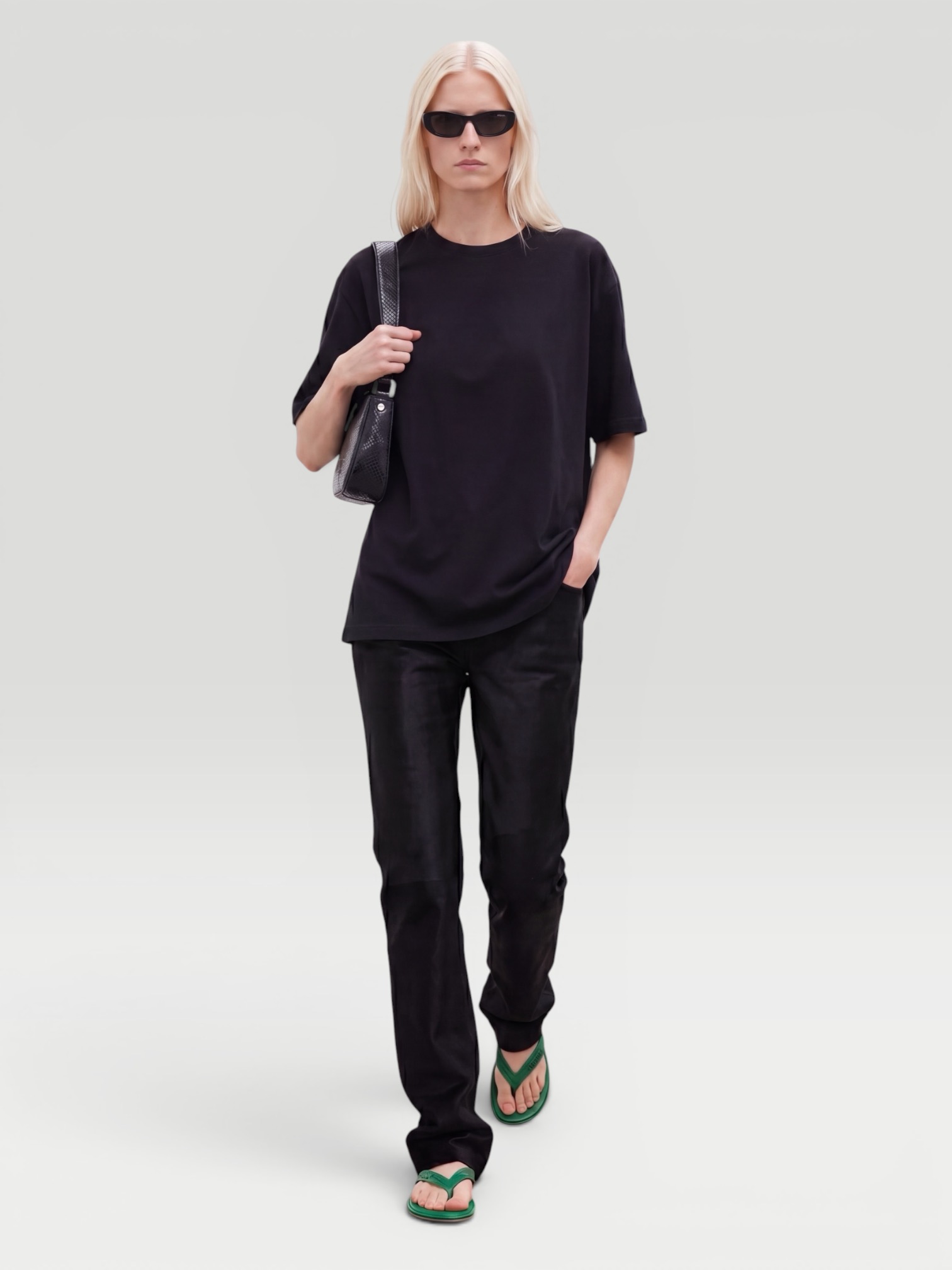 Khaite Mae T-Shirt in black, worn with Phoebe Philo Cotton Wide-Leg Pants, Phoebe Philo Pot Cabas Suede and Leather Tote Bag, Bottega Veneta Drop Chain Necklace, Alaïa Edge Small Cuff Bracelet. Styled by Sharon Lombardo for FDV Concierge.