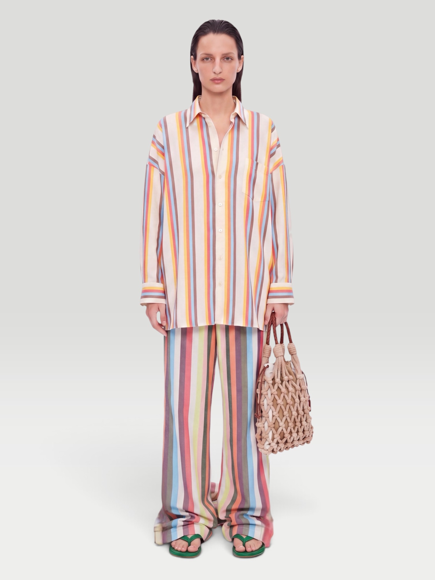 Marrakshi Life The Palazzo Striped Cotton Wide-Leg Pants in multi stripe, worn with Marrakshi Life The Oversized Striped Cotton-Poplin Shirt, Bottega Veneta Sampieri Flat Thong, Prada Noué Medium Cotton Macramé Bag, Dries Van Noten Oval Sunglasses, on the water. Styled by Sharon Lombardo for FDV Concierge.