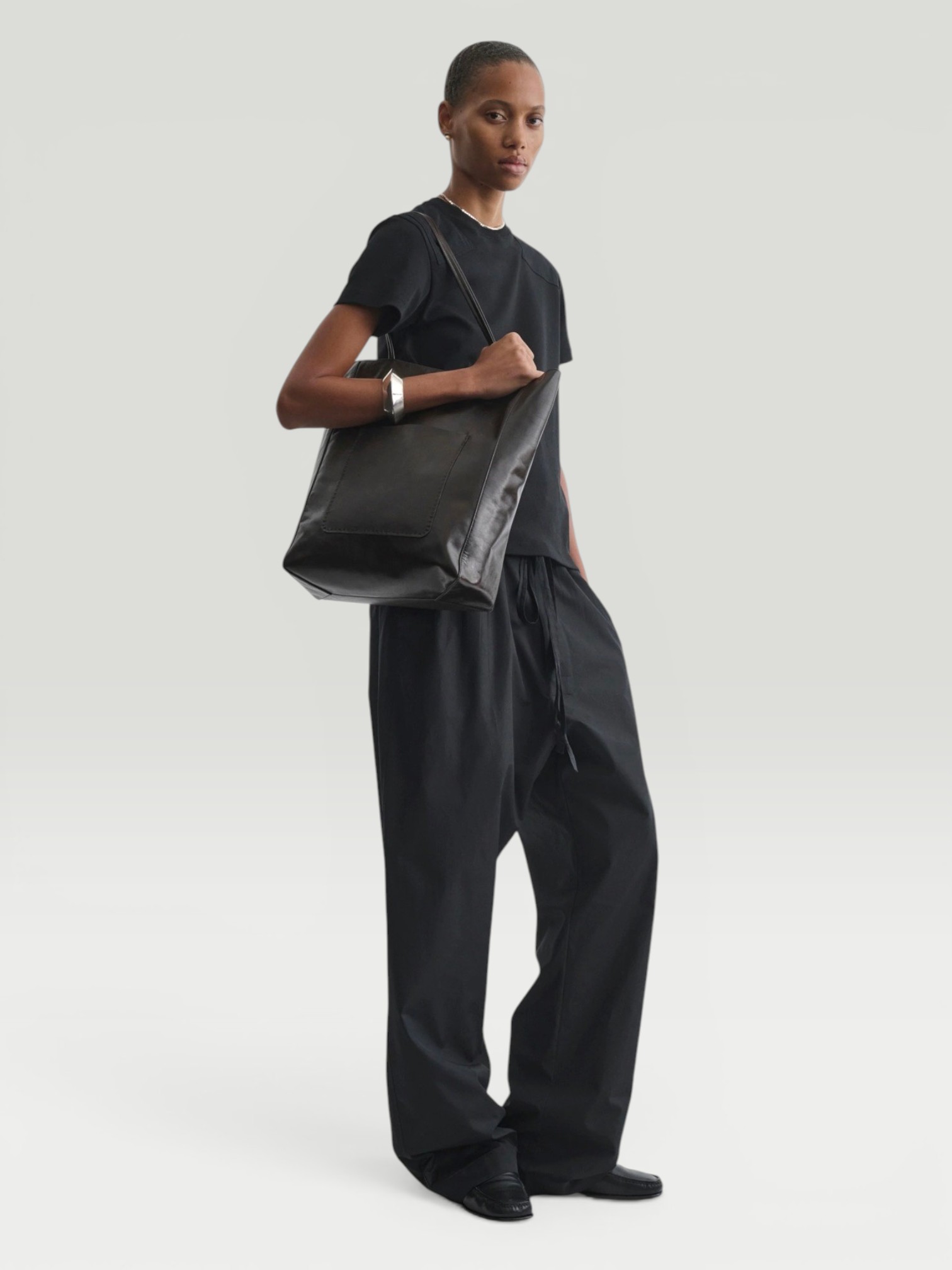 Phoebe Philo Cotton Wide-Leg Pants in black, worn with Phoebe Philo Striped Cotton-Jersey T-Shirt, Phoebe Philo Leather Fisherman Sandals. Styled by Sharon Lombardo for FDV Concierge.