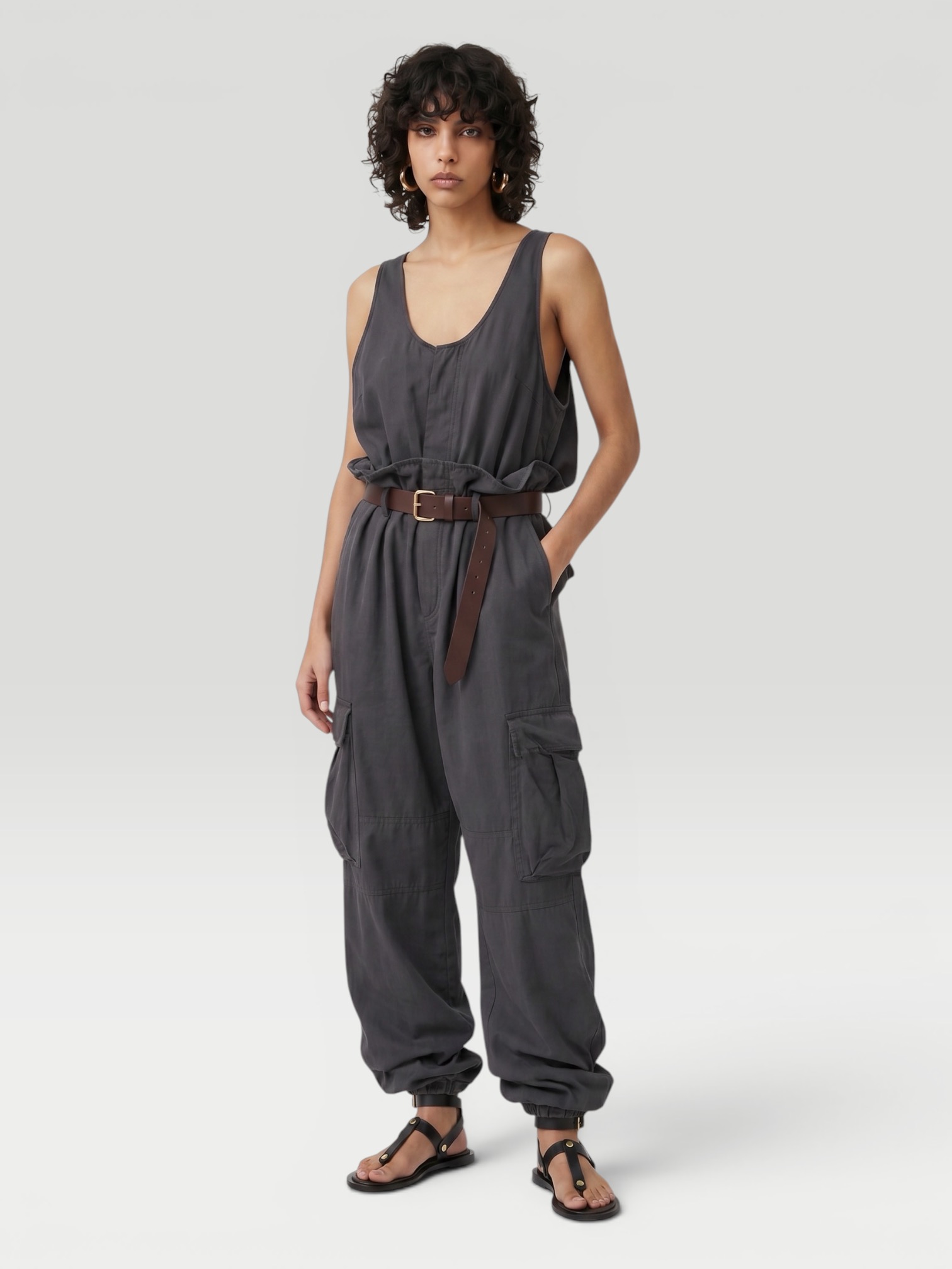 Saint Laurent Cargo Jumpsuit in charcoal, worn with Phoebe Philo Leather Belt, Alaïa Spiral Small Hoop Earrings, CO Ankle Wrap Sandal. Styled by Sharon Lombardo for FDV Concierge.