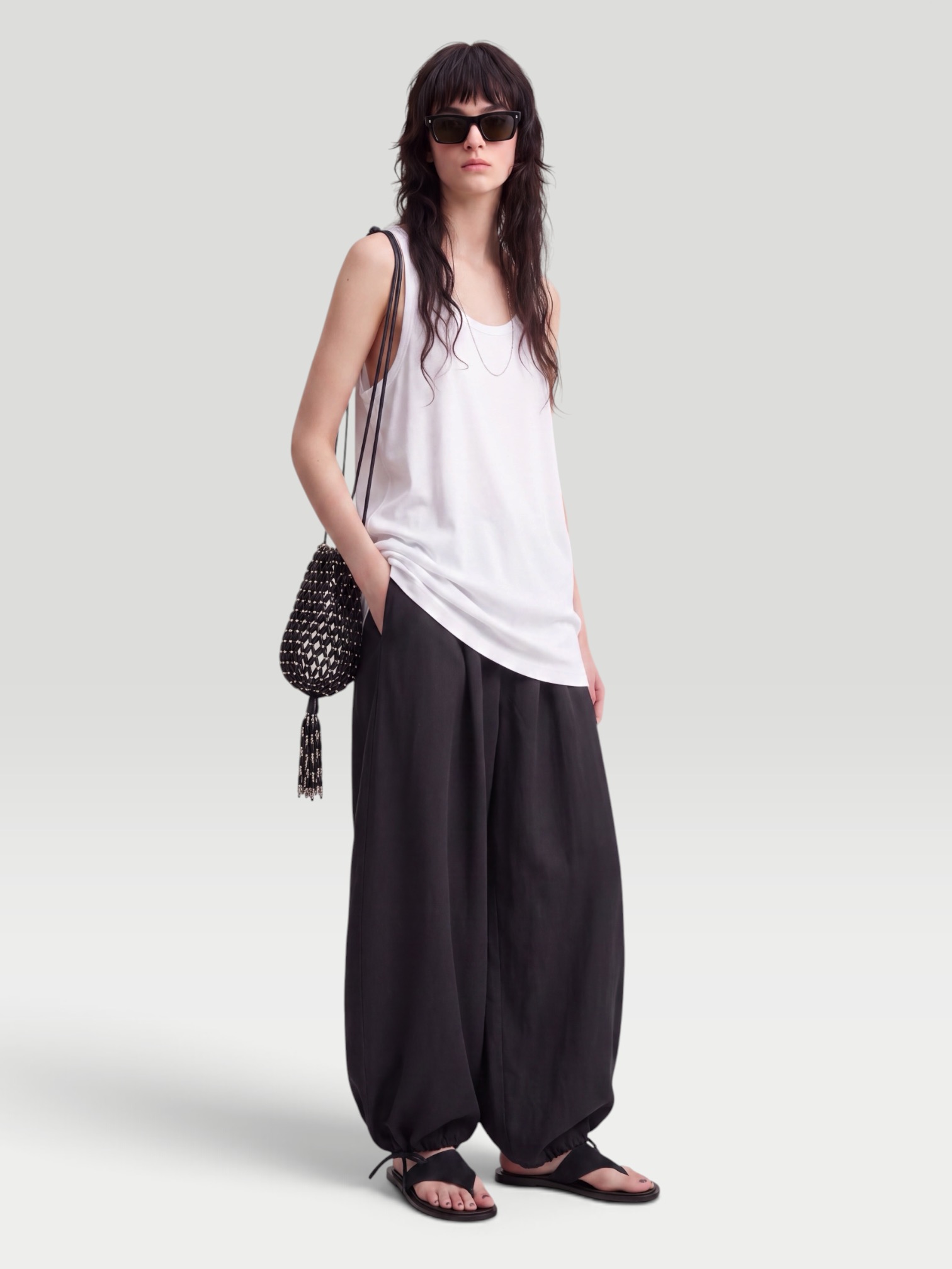 Toteme Lyocell-Blend Tapered Pants in black, worn with Róhe Off Shoulder Lapel Top, Bottega Veneta Salsa Thong, Phoebe Philo Gig Leather Shoulder Bag, Phoebe Philo Bombe Sunglasses, the evening. Styled by Sharon Lombardo for FDV Concierge.